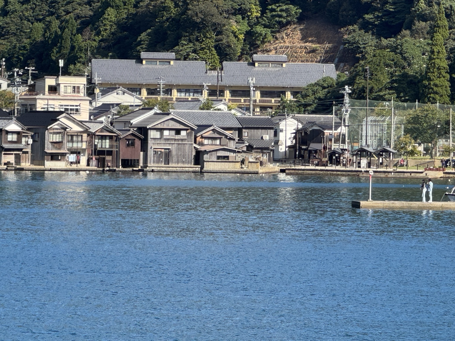 Houses close to the water beneath green hills